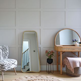 Dressing area with panelled walls, rattan dressing table and leaning floor mirror
