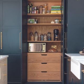 Navy kitchen with built-in pantry in same style.