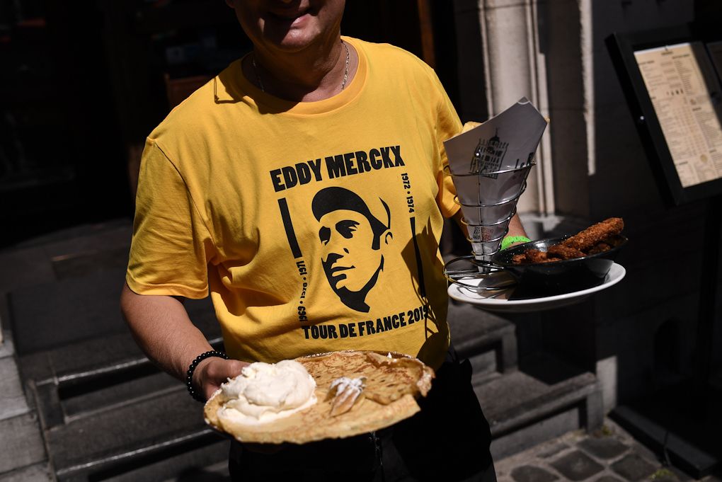 A waiter wearing a yellow Tshirt depicting Belgian legend Eddy Merckx carries food on a terrace of the Grand-Place - Grote Markt Square in Brussels