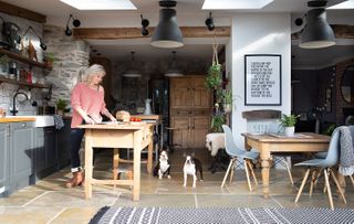 A kitchen extension with stone floor and rooflights, wooden island and table, and exposed brick wall