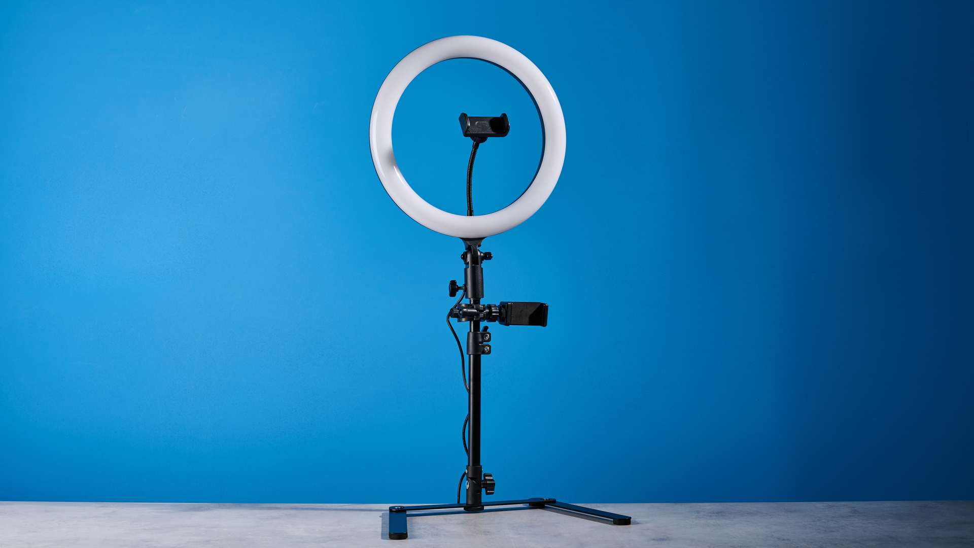 Godox 12-inch ring light photographed in front of a blue background with an iPhone on the phone mount. 