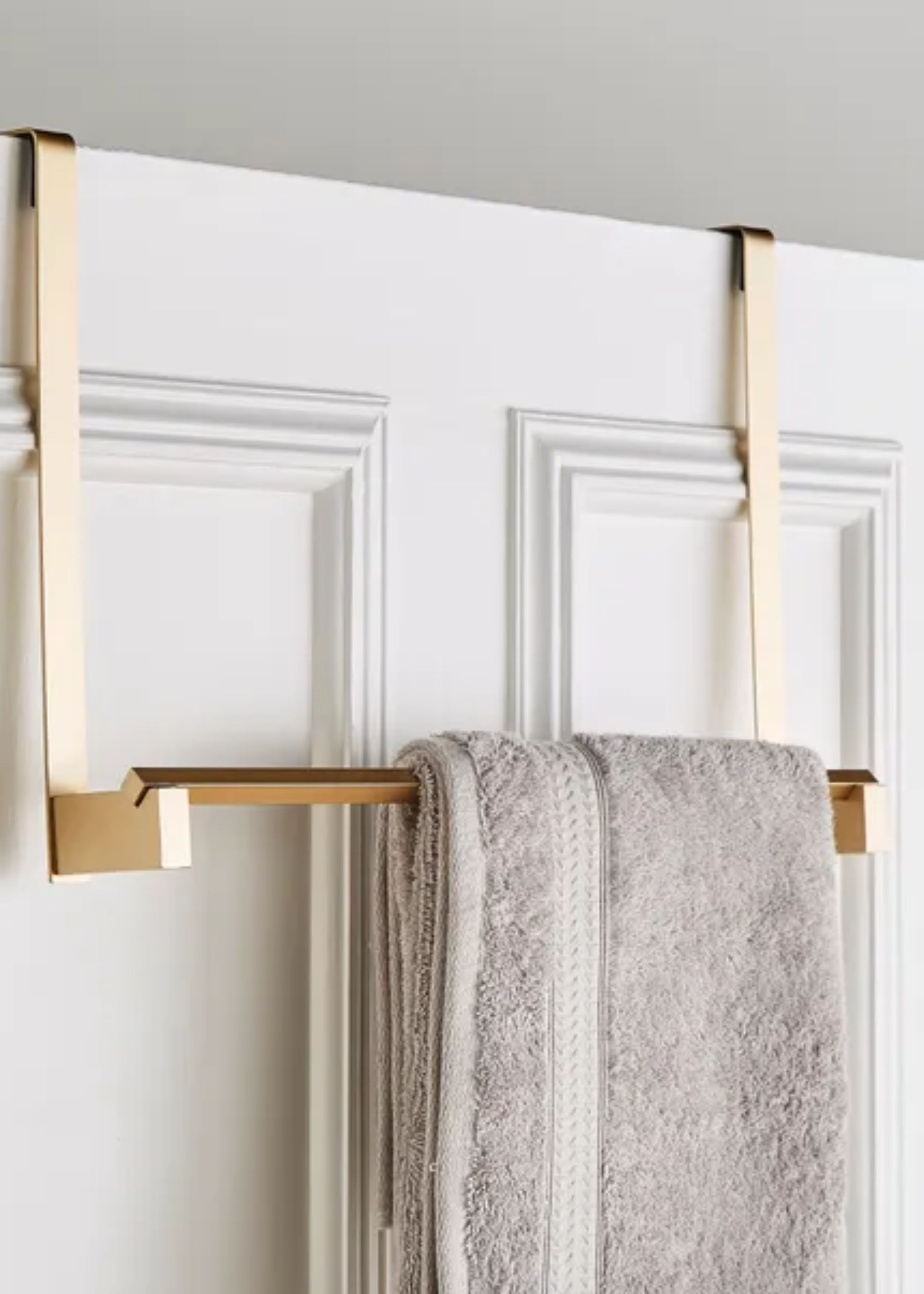 An over the door hanging rack in gold with a towel on it