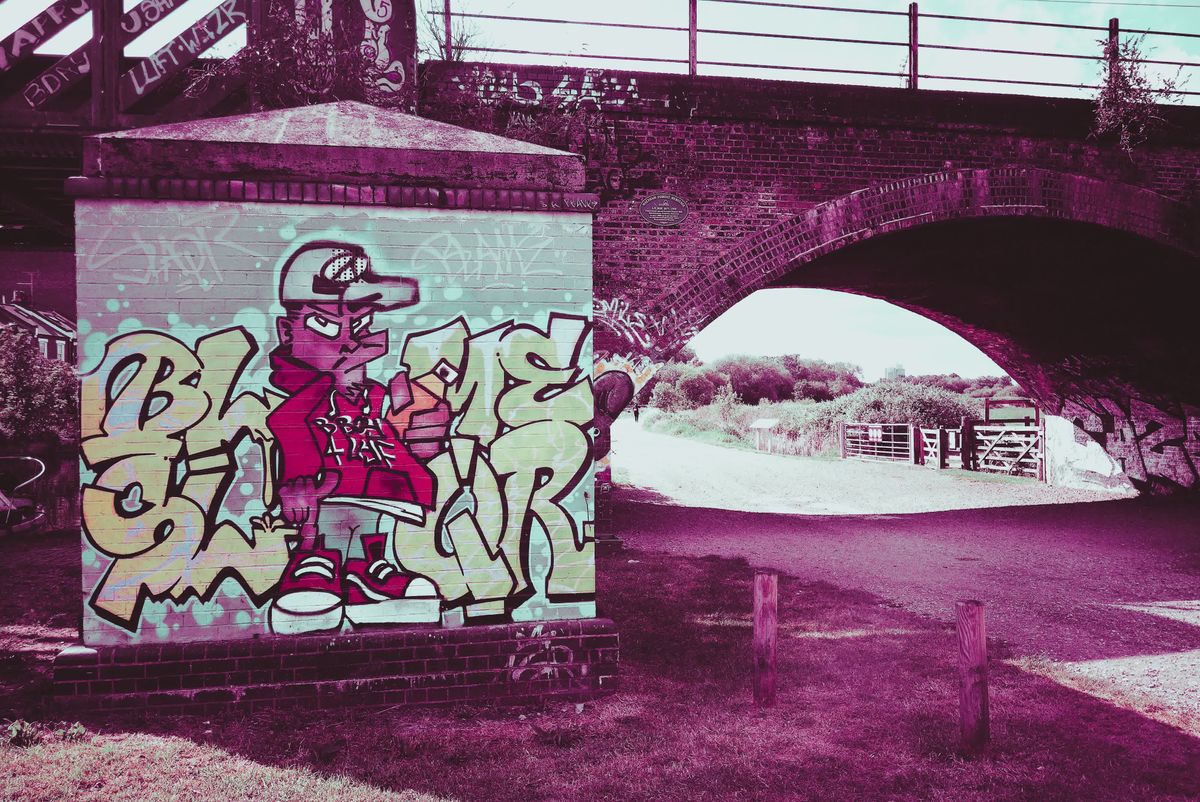 Photograph taken with the RewindPix digital compact showing street art on a bridge with stylised purple tint