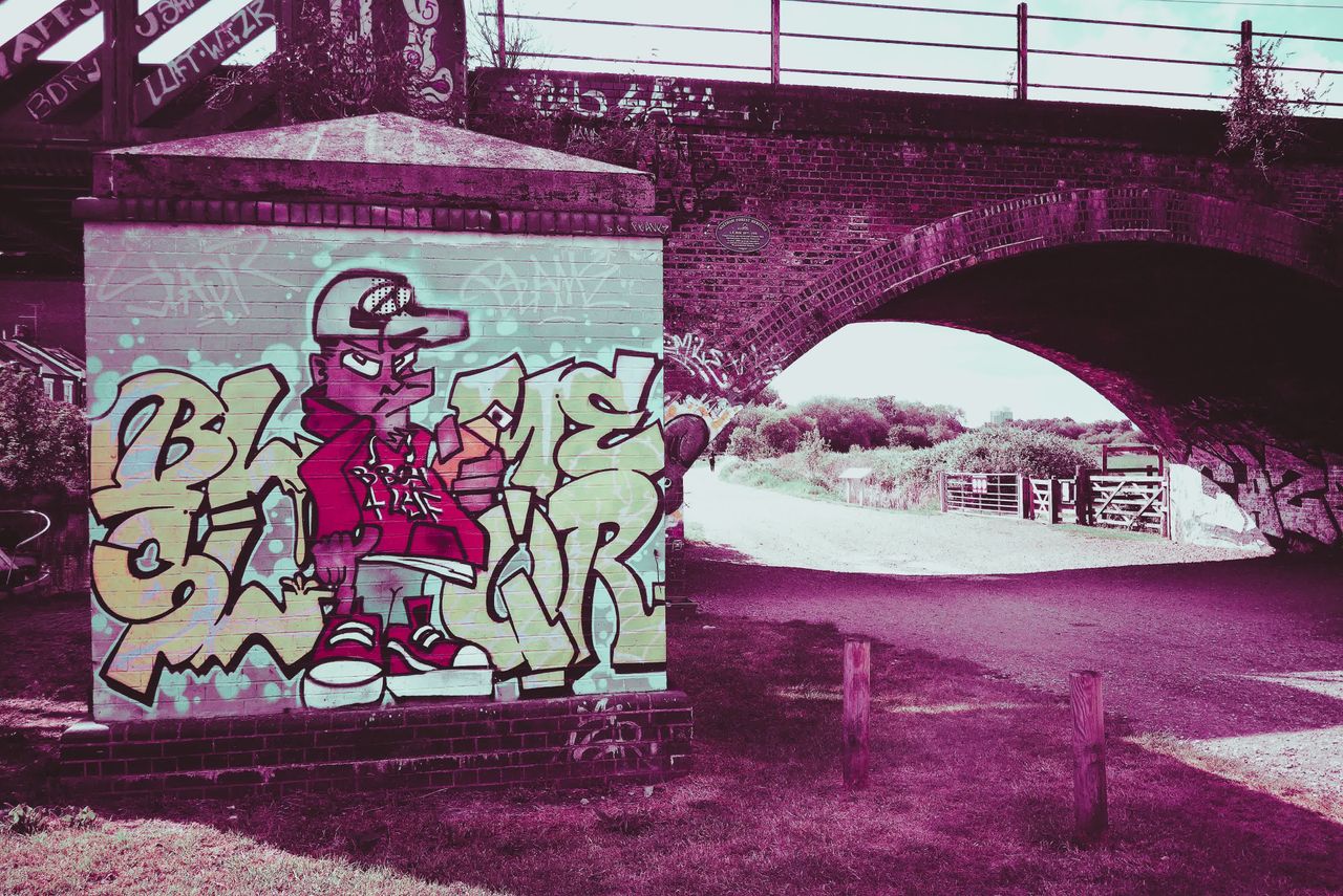 Photograph taken with the RewindPix digital compact showing street art on a bridge with stylised purple tint