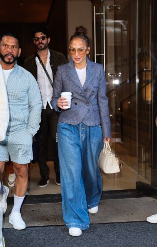 Jennifer Lopez wearing a tailored blue blazer with wide-leg Gucci jeans, white sneakers, and a white Hermès Birkin bag in New York City July 2024