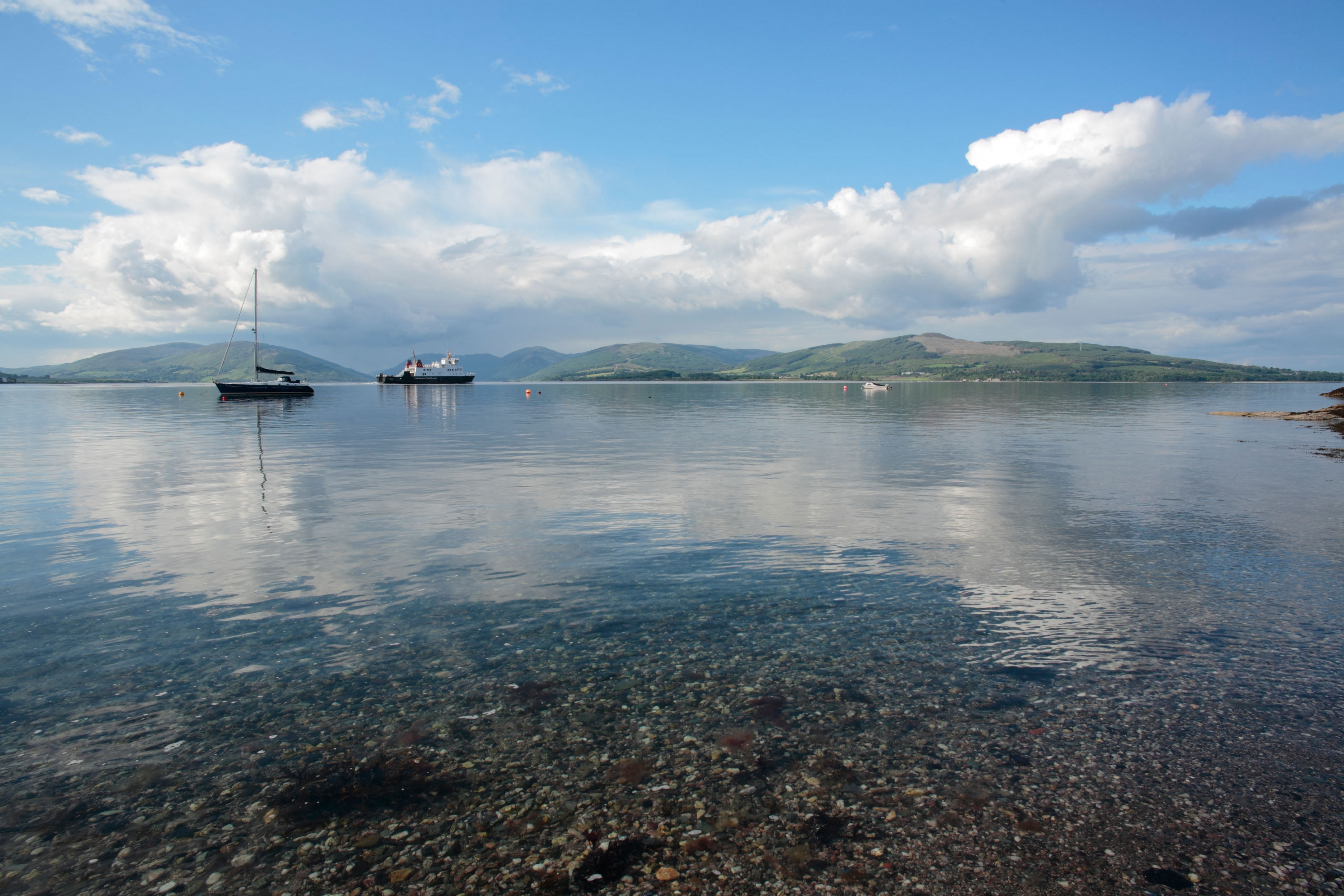 A yacht and ferry crossing Rothesay Bay, part of Loch Striven, with Cowal in the background
