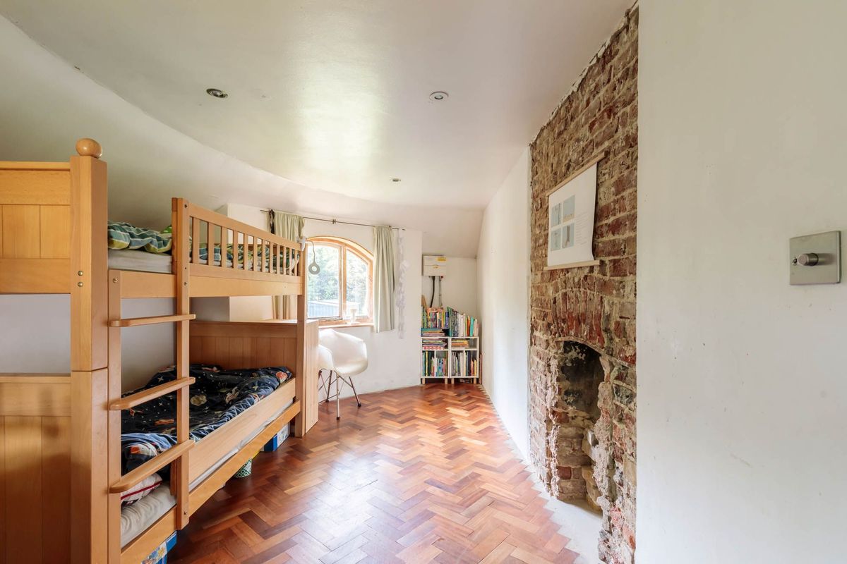 A bunk bed with wooden flooring and a brick fireplace