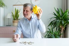 a man shakes and listens to his piggy bank