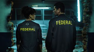 Maeve Jinkings and Romulo Braga sporting Federal jackets facing away from the camera for Criminal Code