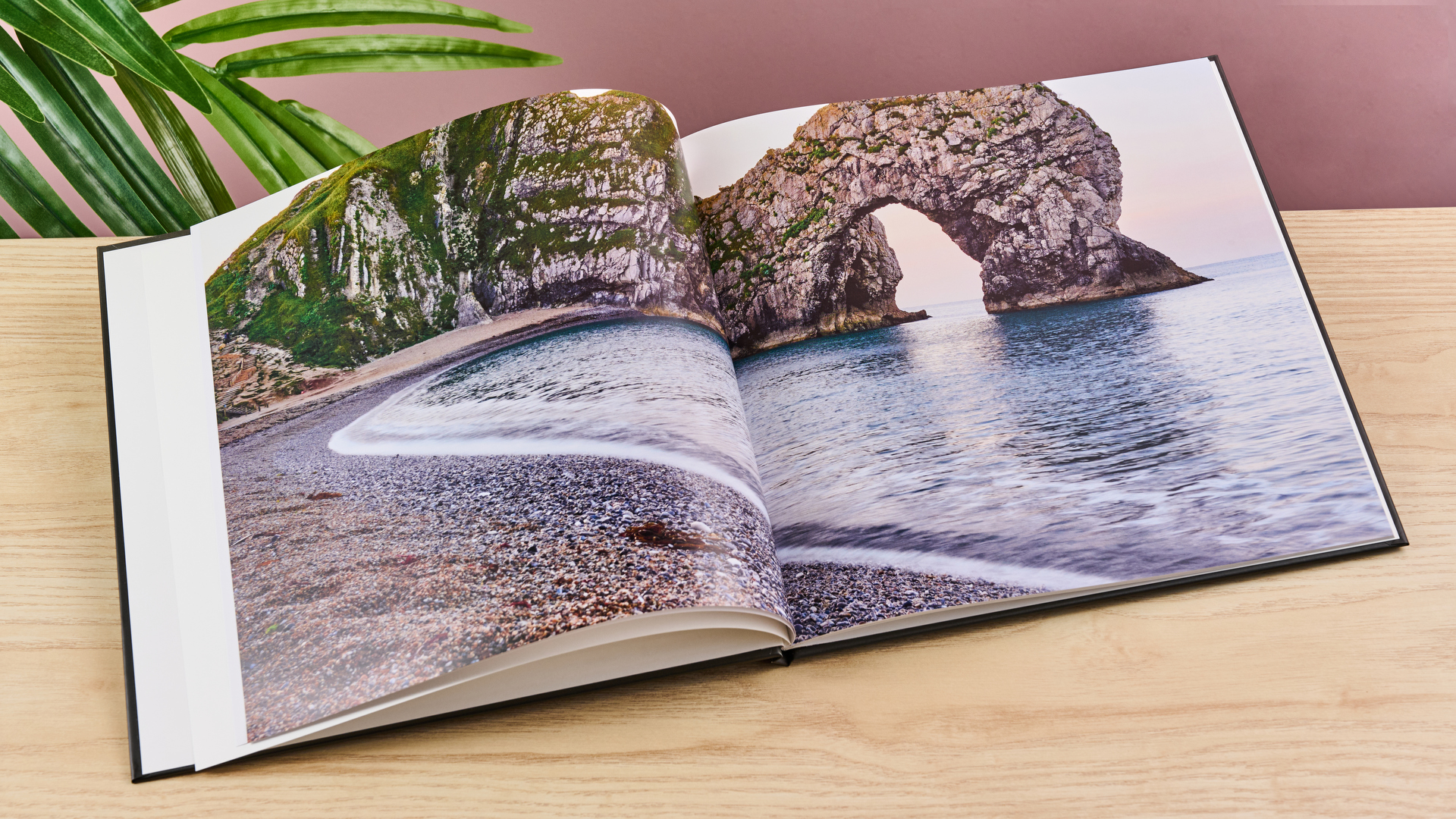 The Once Upon photo book sits open on a two-page spread featuring a pebble beach and cliffs.