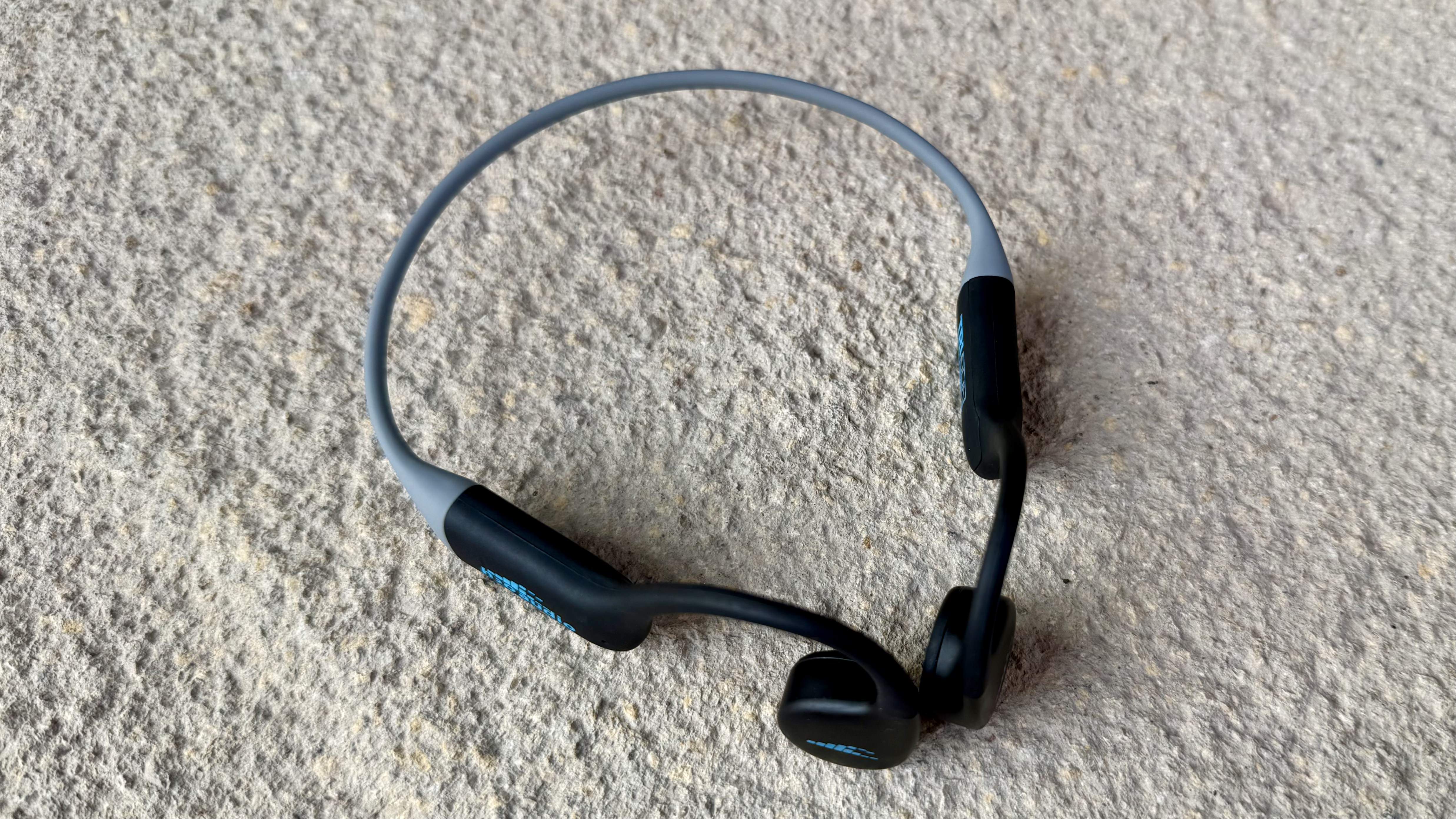 The h2o audio tri run bone conduction headphones on a stone surface