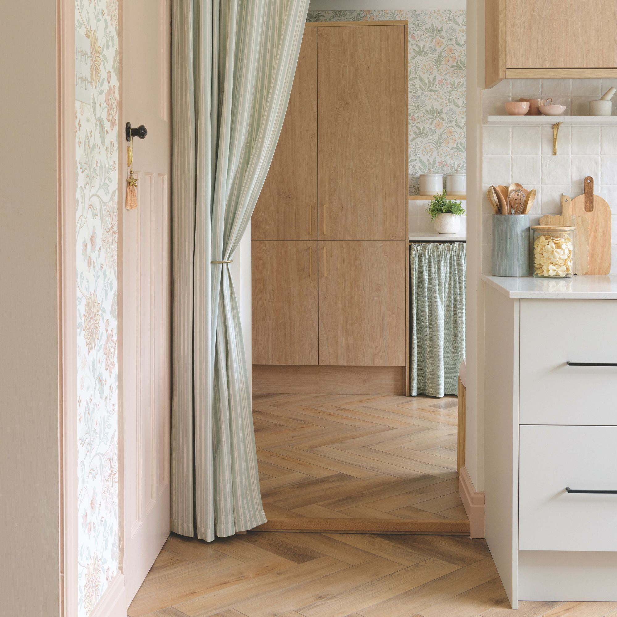 Kitchen area with praquet flooring and a green curtain separating the two sides of the kitchen