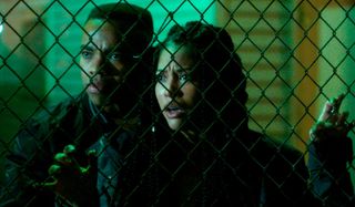 Joivan Wade and Lex Scott Davis concerned behind a chain link fence in The First Purge.