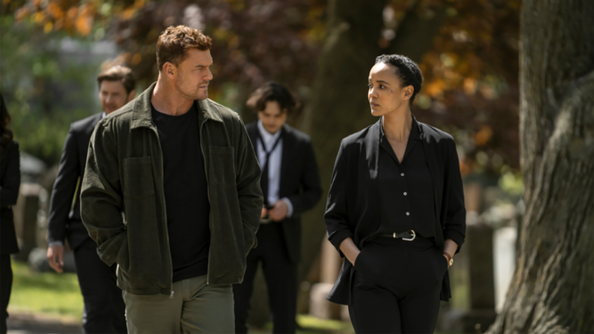 Alan Ritchson looking at Maria Sten while both are walking in the fall in an episode of Neagley Season 1.