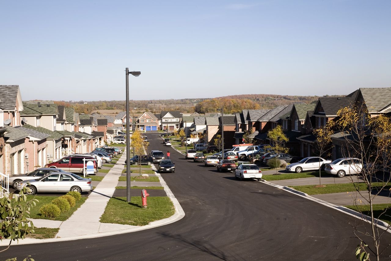 A look down a neighborhood street filled with houses and driveways.