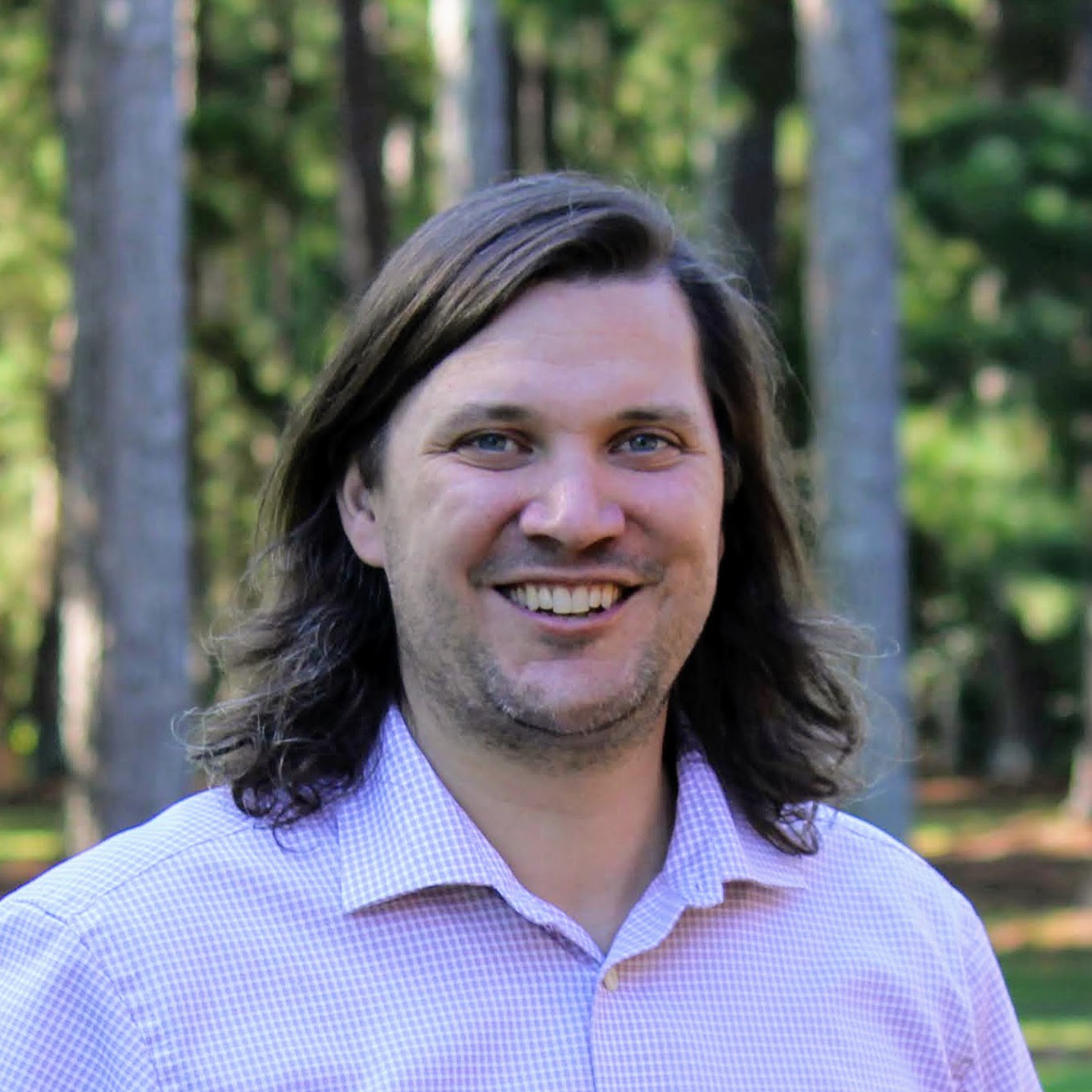 A headshot of Mike Afdahl. He is clean shaven with shoulder length hair.