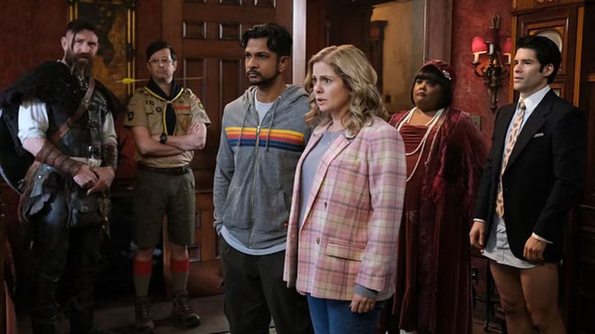 Jay (Utkarsh Ambudkar) and Sam (Rose McIver) flanked by some of the ghost cast in Ghosts US season 3