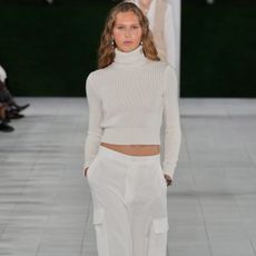 A women at the s/s 25 show wearing linen cargo pants and a sweater.