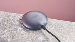 The back of the Anker Wireless Charging Pad, which is sitting on a grey stone-effect surface, against a light pink background.