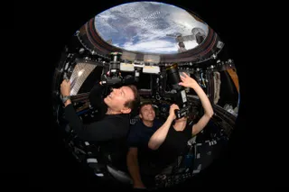 Astronauts taking photographs in the cupola of the International Space Station