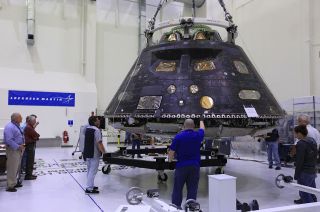 Inside the Neil Armstrong Operations and Checkout Building high bay at NASA's Kennedy Space Center in Florida, the Orion crew module from Exploration Flight Test 1 (EFT-1) is moved from a birdcage test stand to a custom-built transporter for its relocation to nearby Kennedy Space Center Visitor Complex.