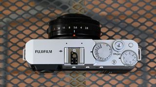 The Fujifilm X-E4 camera from above. The camera is resting on a wire mesh