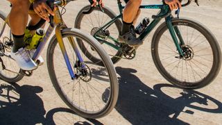 A pair of gravel bikes ride along a dusty track