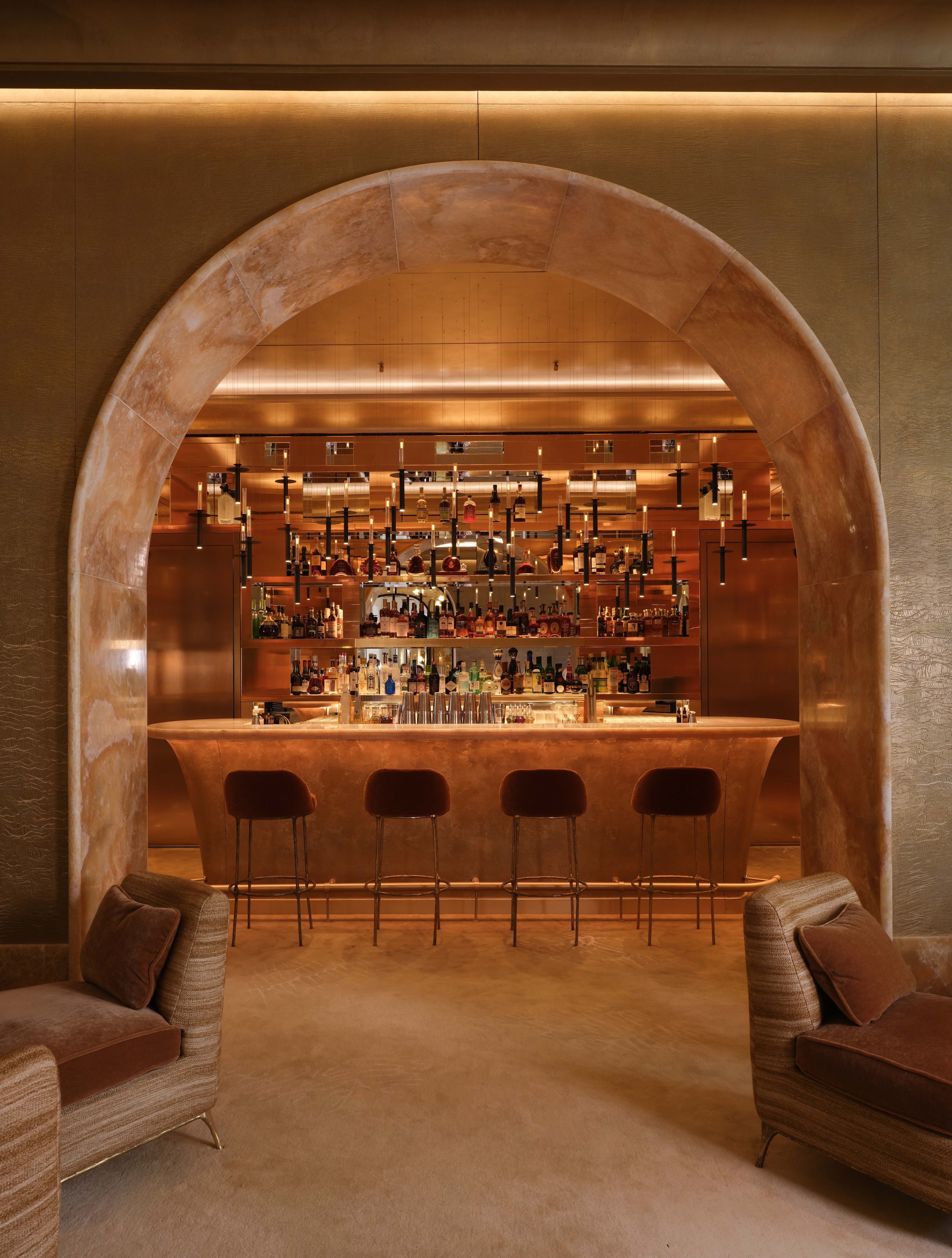 A roman arch lined in stone looks into an amber-drenched bar in Monaco.
