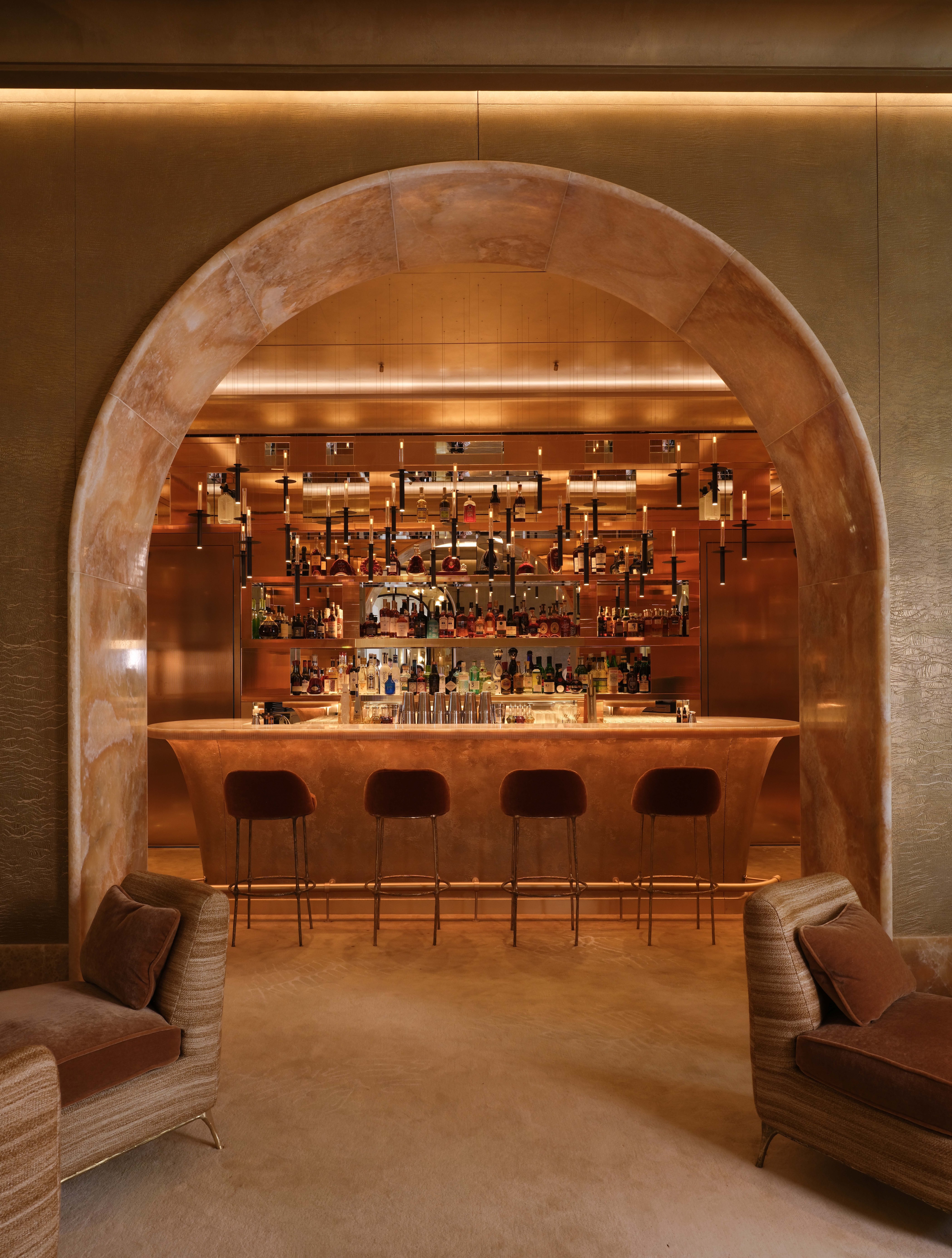 A roman arch lined in stone looks into an amber-drenched bar in Monaco.