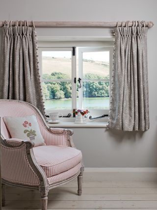 short cottage curtains with trim in traditional home with pink armchair