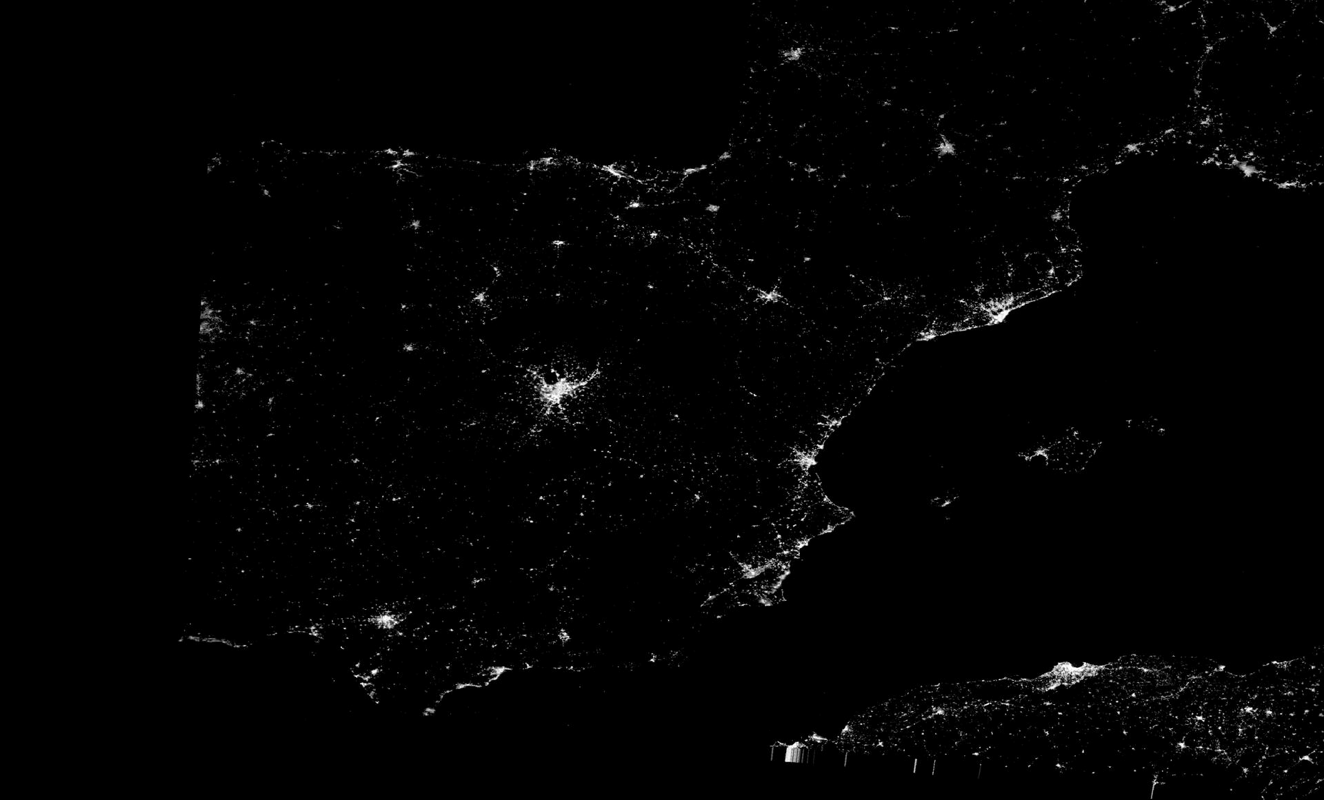 a satellite view of a country at night, dotted with city lights, but containing a dark area where a power blackout occurred