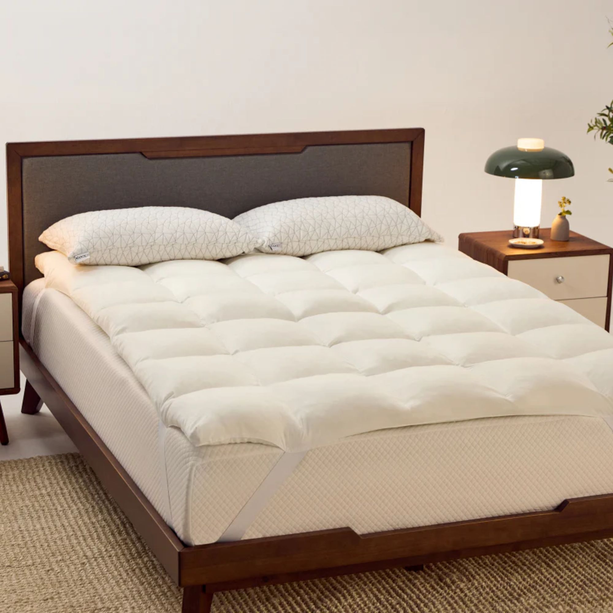 Coop mattress topper on a dark wood bed in a white bedroom with a jute rug.