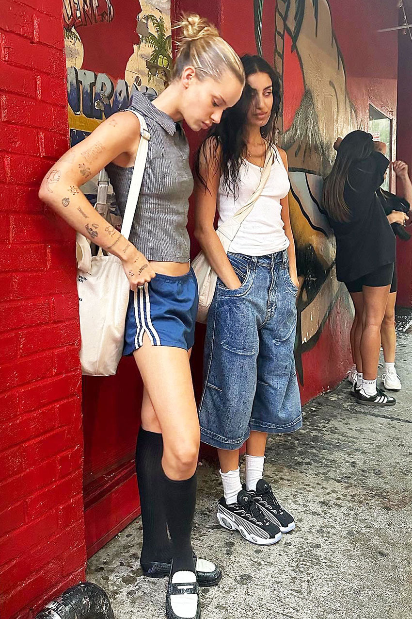A woman wearing a white tank top, denim culotte pants, and gray sneakers