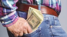 An older man puts cash in his back pocket.