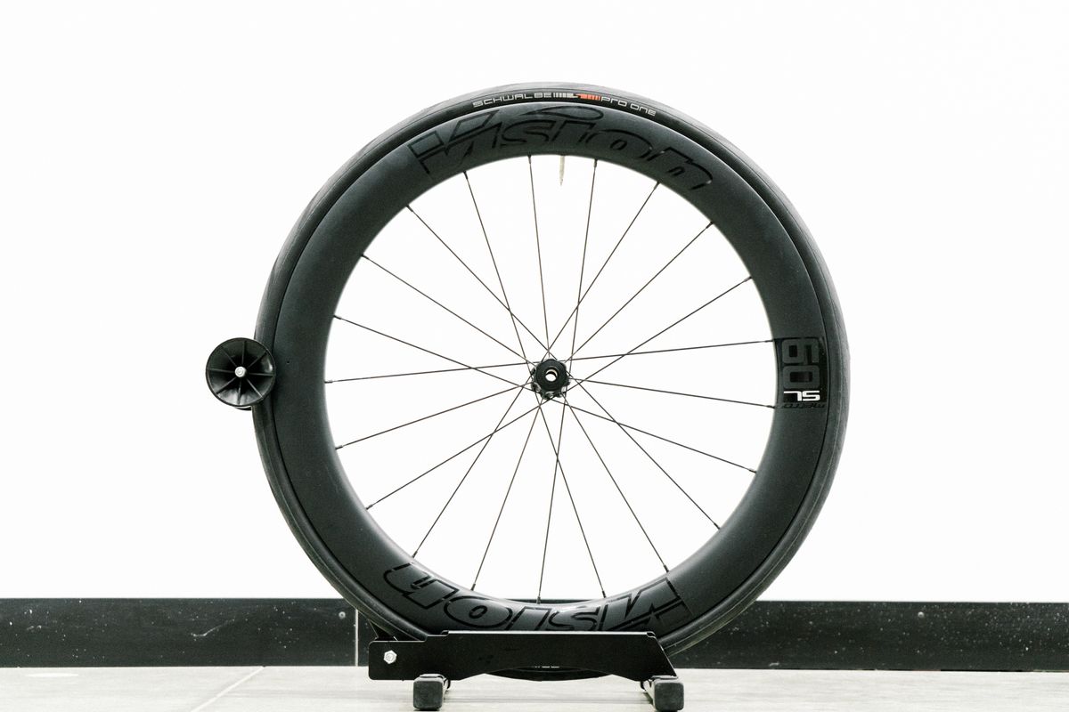 An aero road wheel stands against a white wall