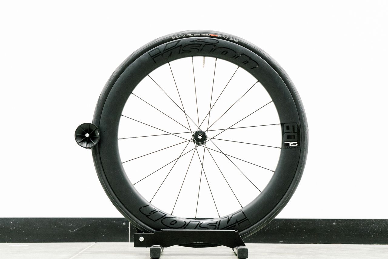 An aero road wheel stands against a white wall