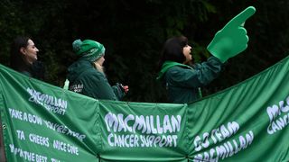 People by a Macmillan Cancer Support banner cheer on runners in the London Marathon