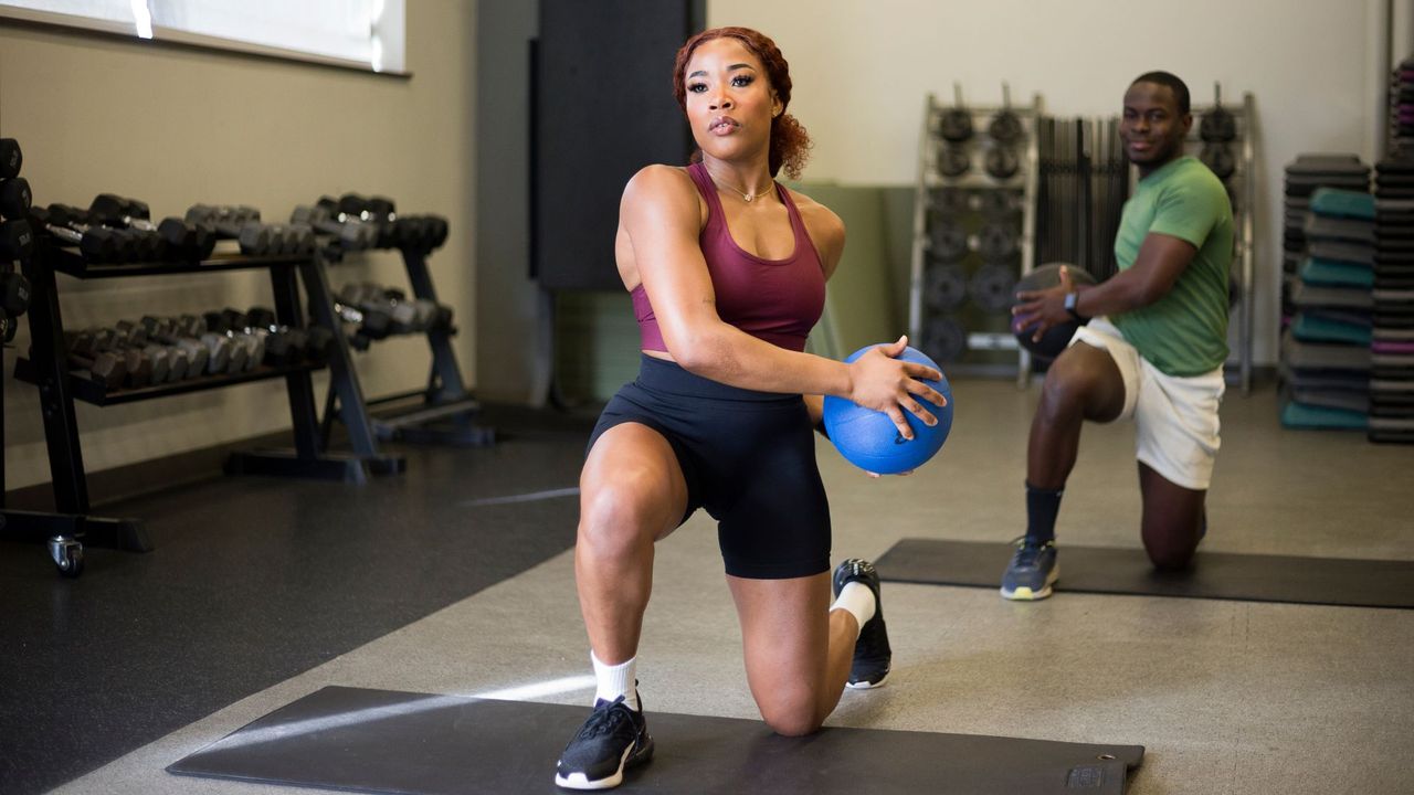 A woman working out with a medicine ball at a gym