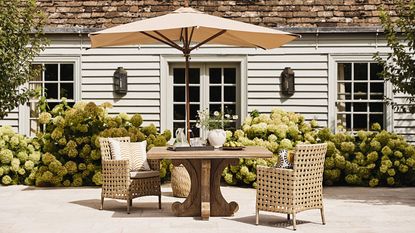 patio table, chairs and umbrella on a patio by a pool