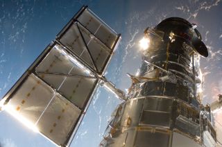 A silvery spacecraft with a solar panel wing above Earth.