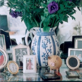 glass table with photo frames and piggy bank