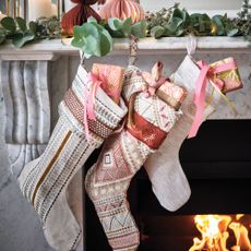 Stockings with patterns hanging infront of a fireplace