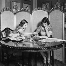 Princess Margaret Rose (1930 - 2002) and Princess Elizabeth (right) working on paintings in the school room of Buckingham Palace