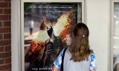 A woman in Maine examines a poster for the new Batman movie, The Dark Knight Rises, after the horrific shooting that killed 12 innocent movie goers in Colorado.