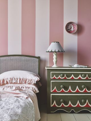 pink and white striped walls in a bedroom with painted chest of drawers