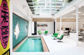 Inside open plan pool area next to green wall surrounded by green chairs
