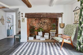 hallway with fireplace and geometric rug and midcentury chair cover with beams