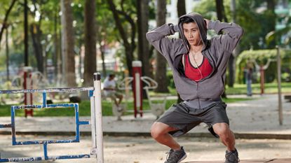 Man in a park doing deep squat