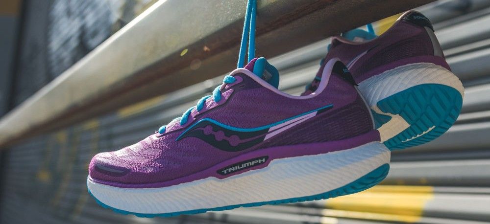 Saucony Triumph 19 running shoes in pink hanging from a metal rail