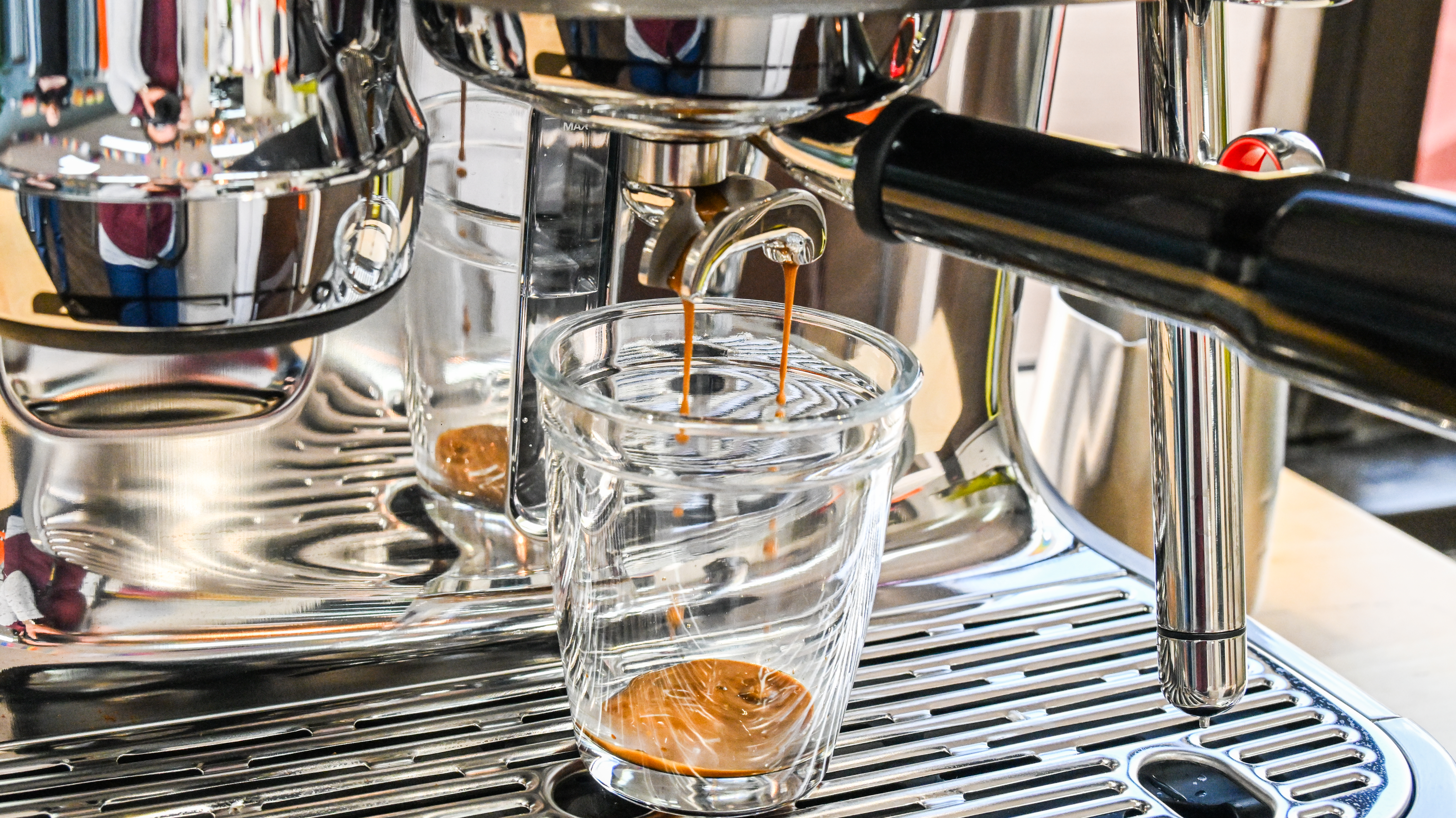 A close up of the Breville Oracle Jet coffee machine's portafilter in the process of extracting a shot of coffee.